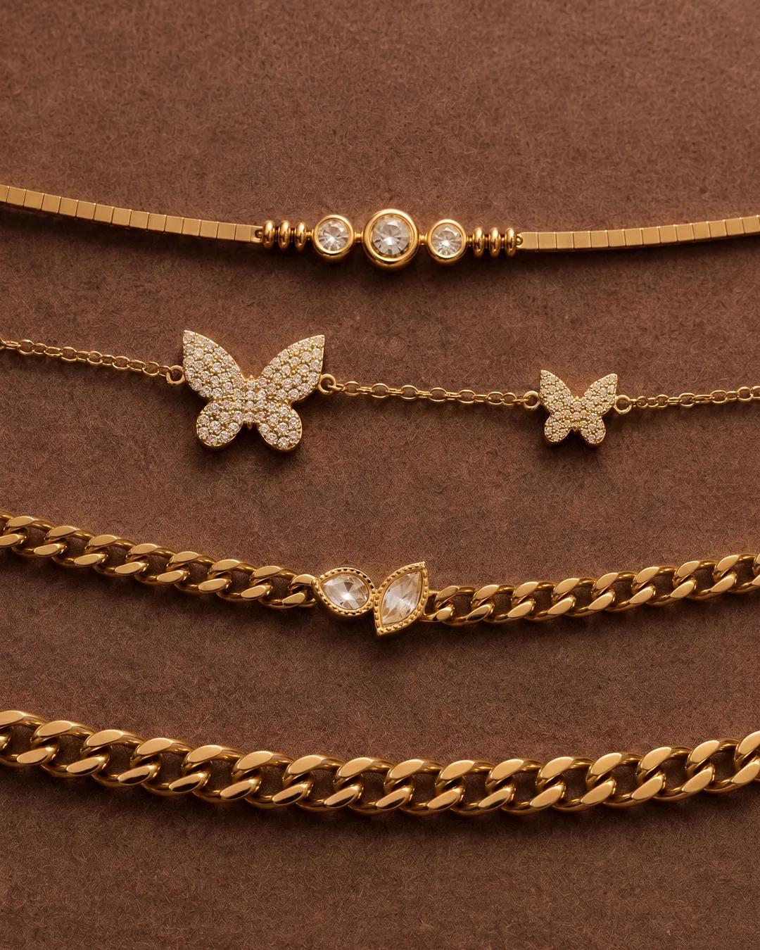 Stacked gold bracelets on a brown leather ground
